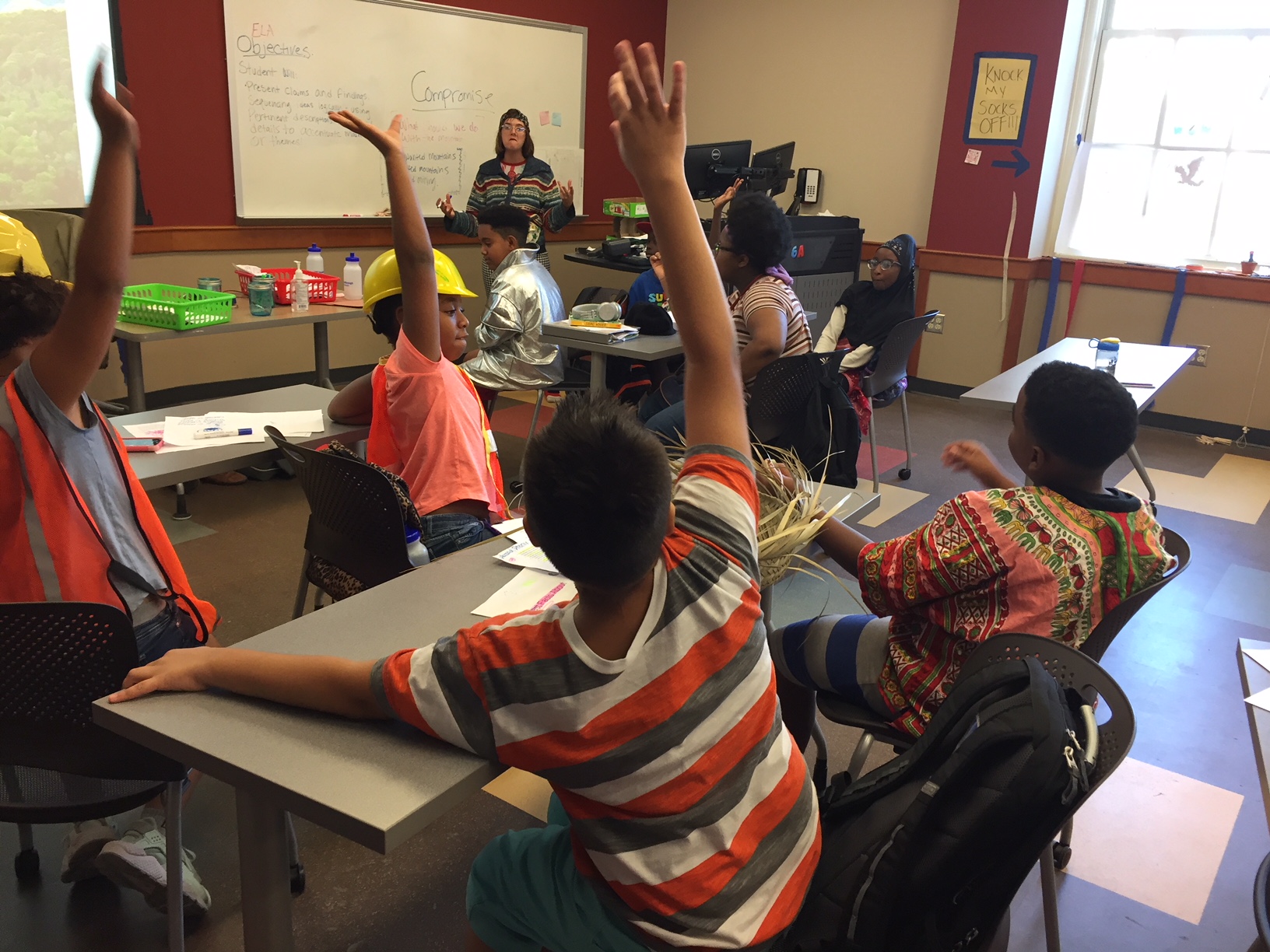 student raising his hand to ask a question in classroom