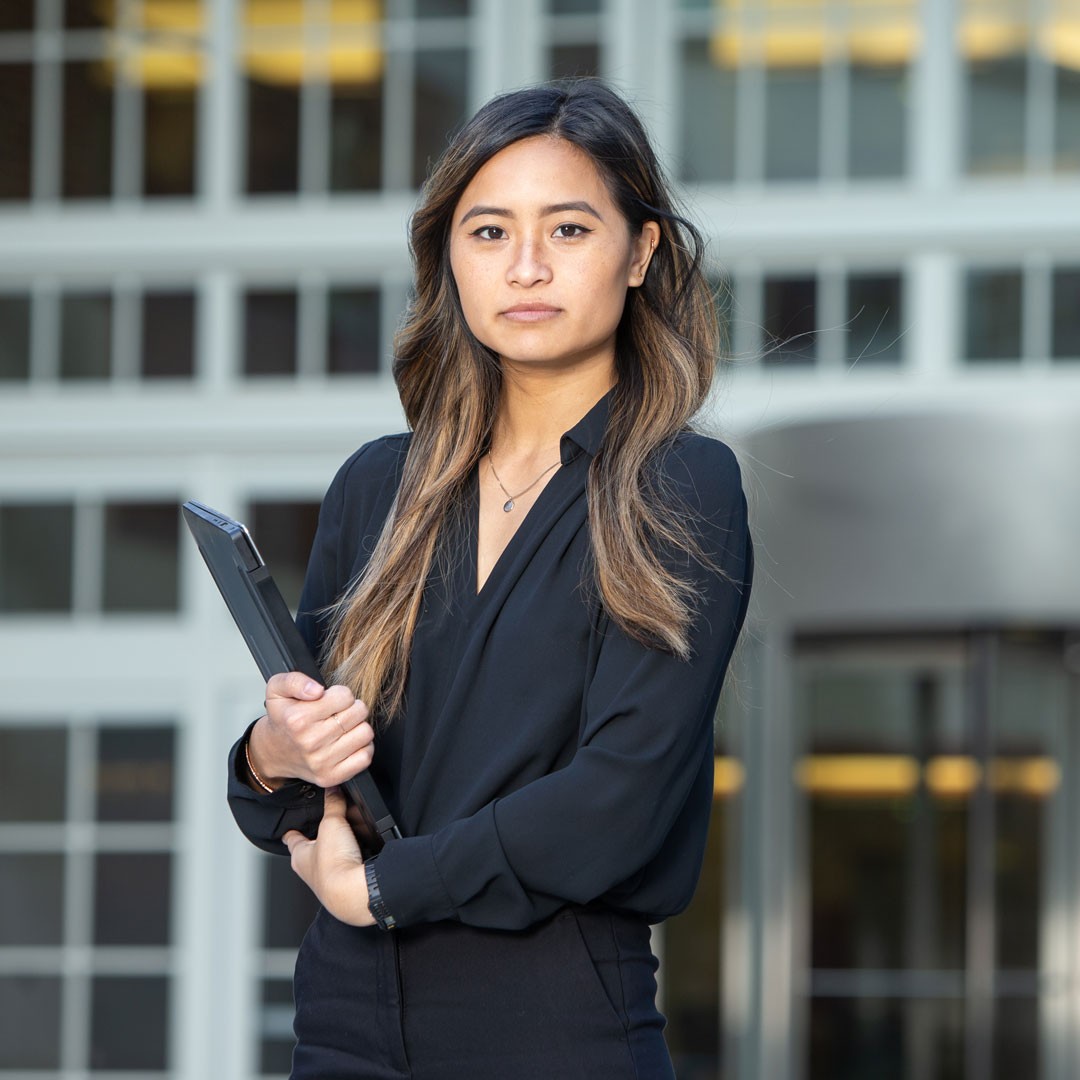 young woman stands with closed laptop
