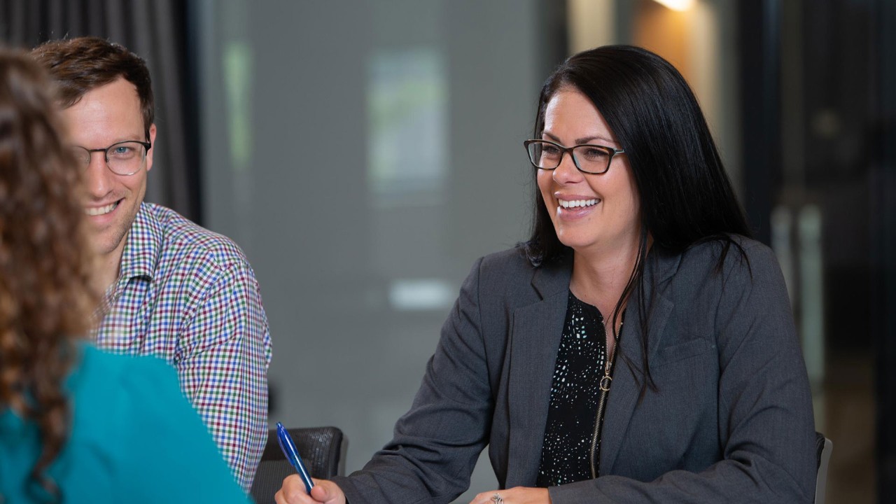 Professionals sit in discussion and smiling